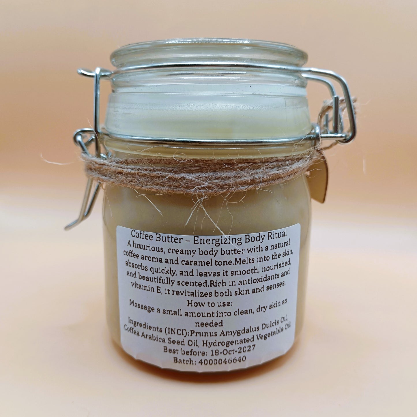 Glass jar with a lid containing a product labeled 'Coffee Butter' on a beige background