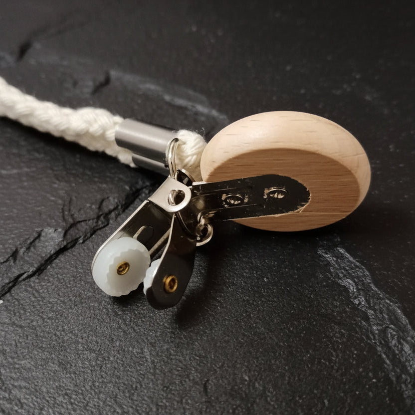 Close-up of a wooden towel hanger with metal clip on a dark gray background