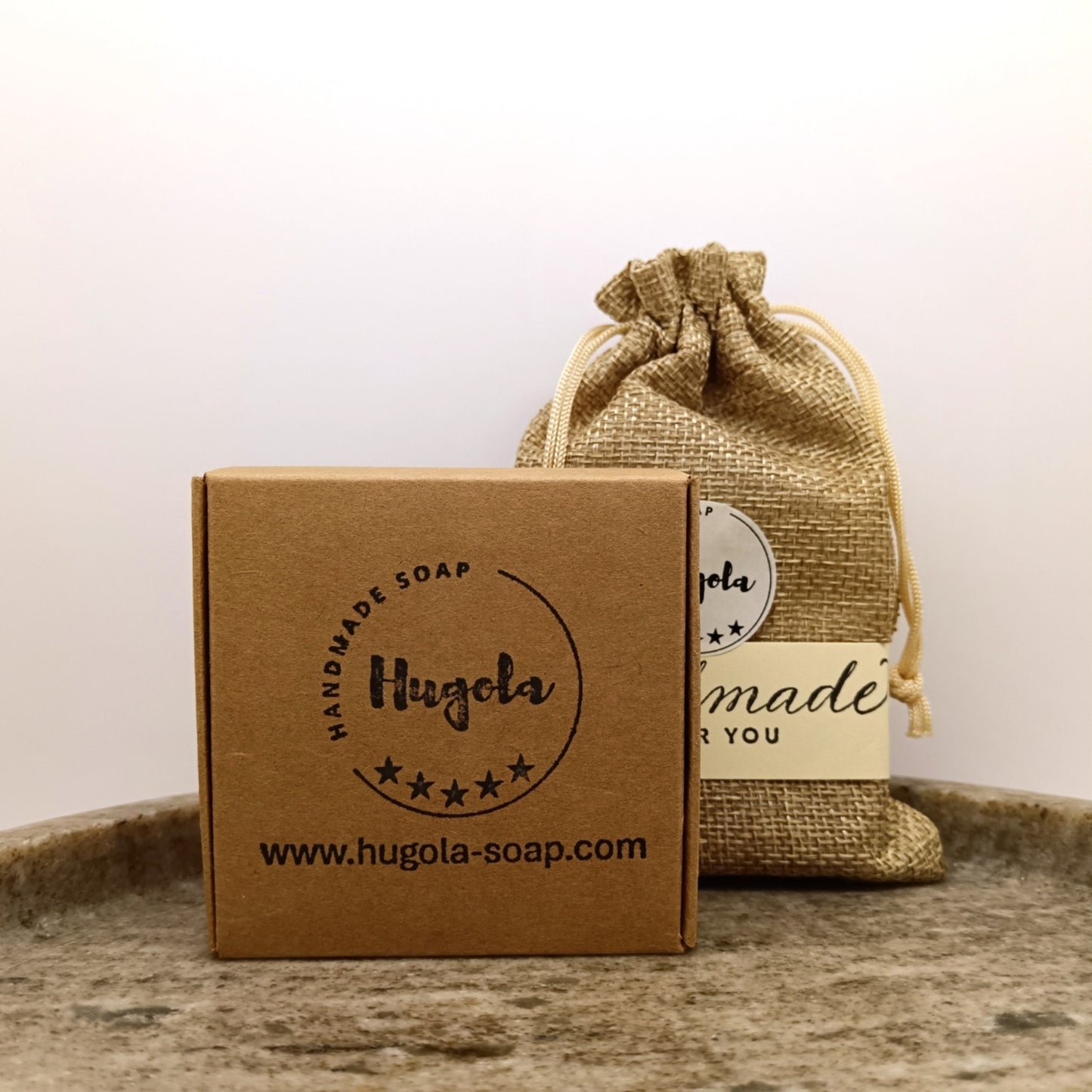 Hugola handmade soaps: one in a brown eco friendly paper box and second one in jute bag
