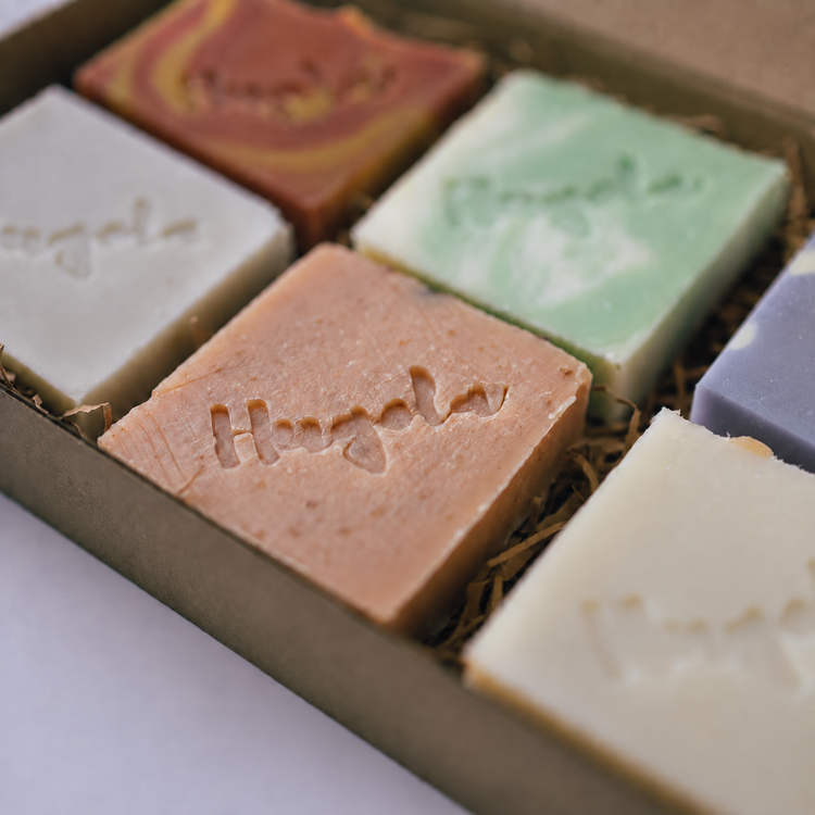 A close-up of a Hugola gift box containing several artisanal handmade soaps in different colors.