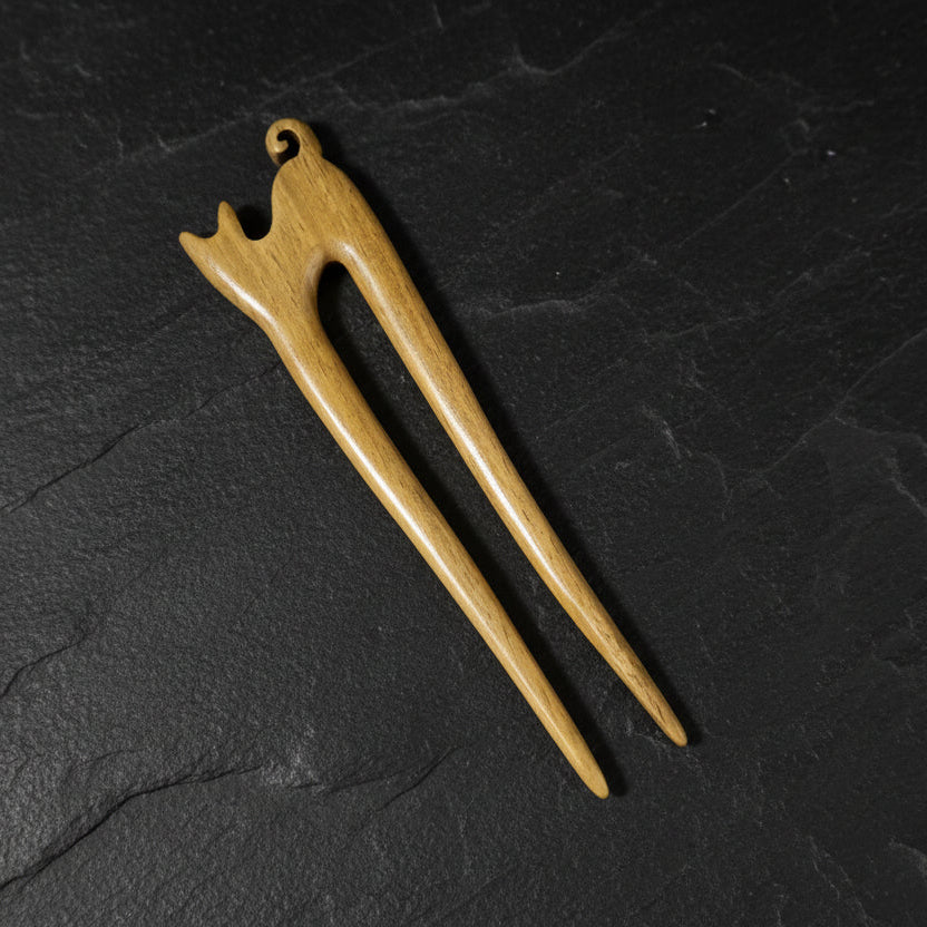 Wooden cat-shaped hair pin on a dark gray background