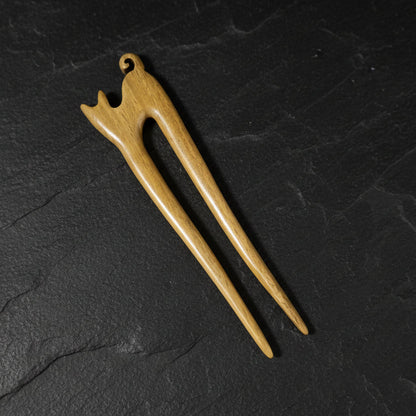 Wooden cat-shaped hair pin on a dark gray background