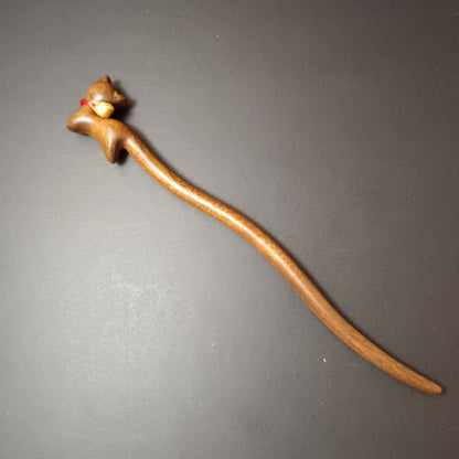Wooden hair stick with bell on a gray background