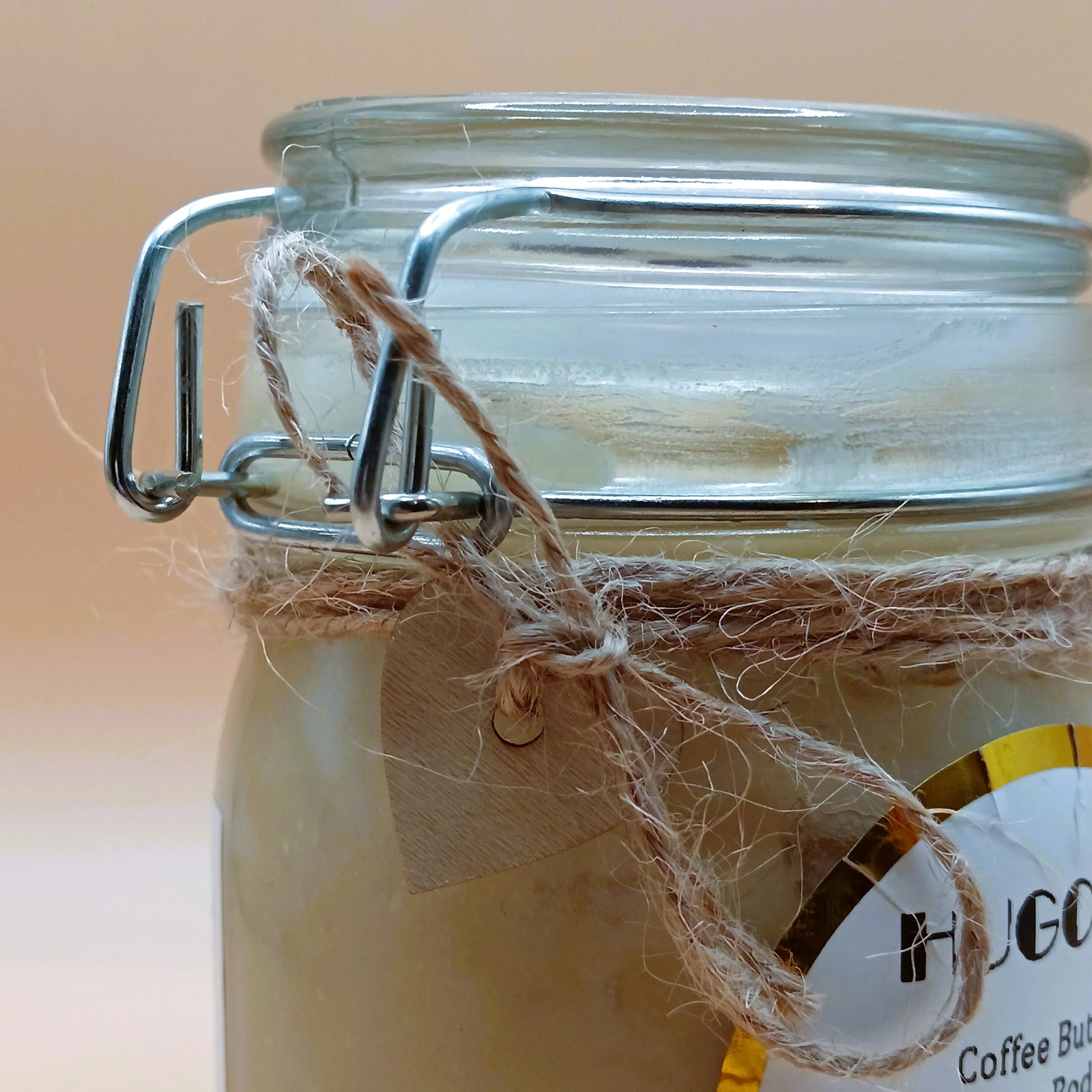 Close uo to glass jar with a metal clasp and twine, featuring a label with text.