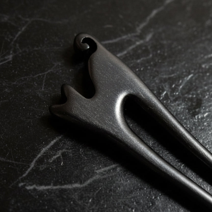Close-up of a wooden cat shape hair pin on a gray background