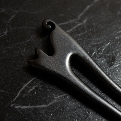 Close-up of a wooden cat shape hair pin on a gray background