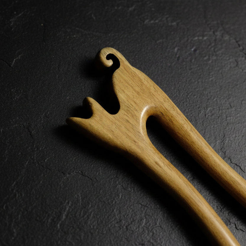 Close up to wooden cat shaped hair pin on a gray background