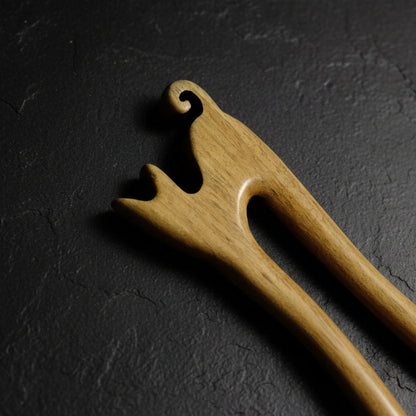 Close up to wooden cat shaped hair pin on a gray background