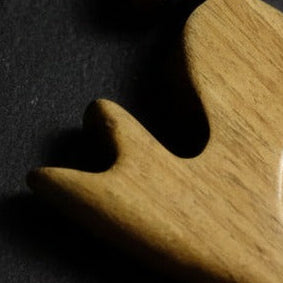 Close-up of a wooden object with a heart-shaped cutout on a dark background