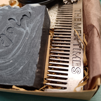 Bar of soap and metal comb with 'The Men Times' branding on a textured surface.