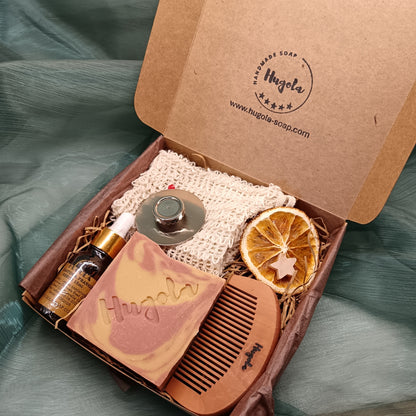 Grooming kit with soap, comb, and other items in a Hugola branded box on a green fabric background.