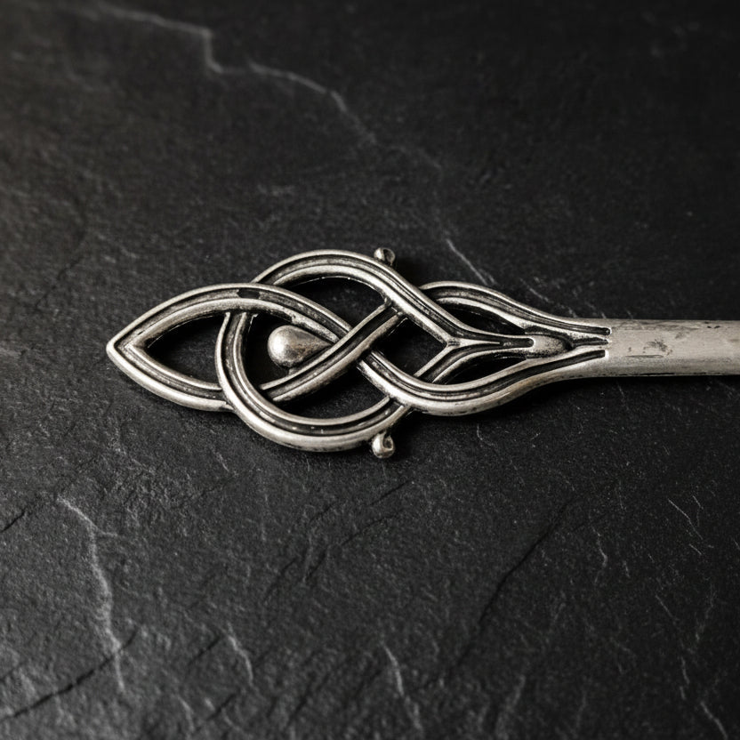 Silver hair clip with intricate design on a dark gray background