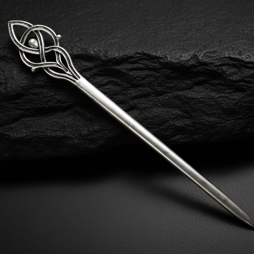 Silver decorative hairpin on a dark gray background
